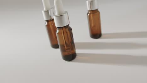 Close-up-of-three-glass-bottles-with-pumps-with-copy-space-on-white-background