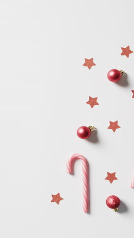 Vertical-video-of-candy-cane-with-christmas-decorations-and-copy-space-on-white-background