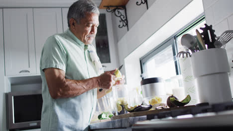 Happy-senior-biracial-man-preparing-healthy-drink-in-kitchen