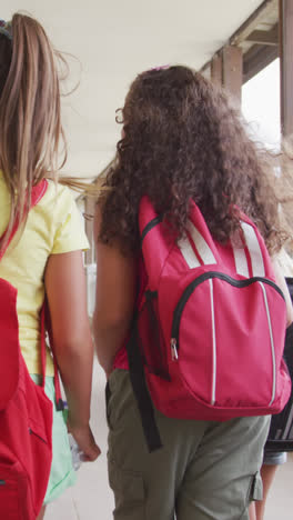 Video-of-back-view-of-diverse-girls-walking-at-school-corridor-and-talking