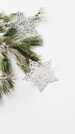 Vertical-video-of-fir-tree-branch-with-christmas-decorations-and-copy-space-on-white-background