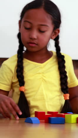 Vertical-video-of-a-biracial-girl-playing-with-colorful-blocks-at-home