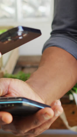 Video-of-hands-of-caucasian-woman-paying-with-smartphone-in-organic-grocery-shop