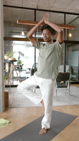 Vertical-video-of-african-american-man-doing-yoga-and-meditating-at-home,-slow-motion