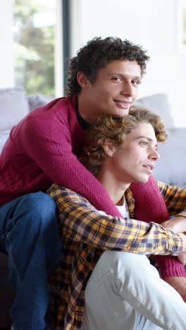 Vertical-video-of-portrait-of-happy-diverse-gay-male-coupleembracing-at-home,-slow-motion