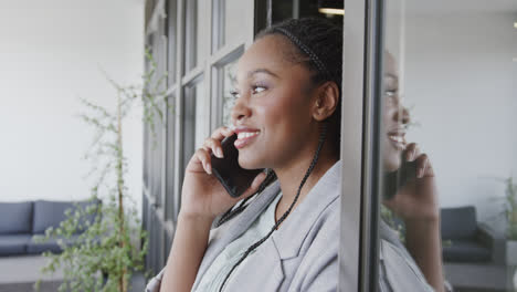 Happy-african-american-casual-businesswoman-talking-on-smartphone-in-office-lounge,-slow-motion