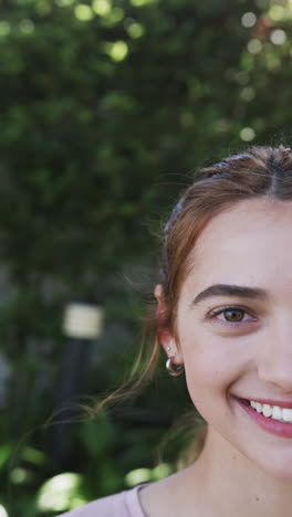 Media-Cara-De-Una-Mujer-Caucásica-Feliz-Parada-Y-Sonriendo-En-Un-Jardín-Soleado,-Cámara-Lenta