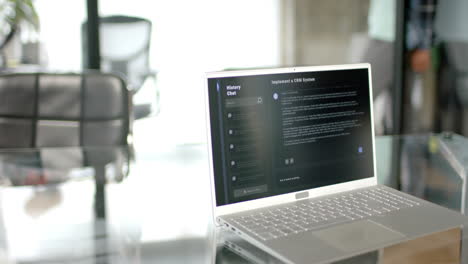 Close-up-of-desk-with-smartphone,-laptop-with-ai-chatbot-and-mug-of-coffee-at-home,-slow-motion