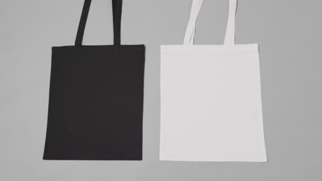 Close-up-of-white-and-black-bags-on-grey-background,-with-copy-space,-slow-motion