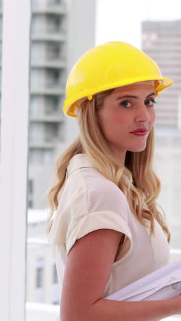 Vertical-video-of-a-young-Caucasian-woman-in-a-hard-hat-looks-to-the-side,-with-copy-space