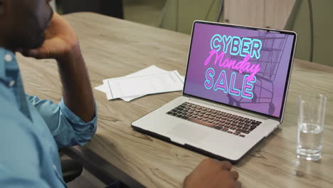 African-american-man-at-table-using-laptop,-online-shopping-during-cyber-monday-sale,-slow-motion