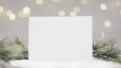 Video-of-christmas-decorations-and-white-card-with-copy-space-on-snow-background