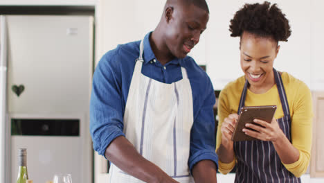 Video-Eines-Glücklichen-Afroamerikanischen-Paares,-Das-Zusammen-Mit-Einem-Tablet-Kocht