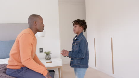 Happy-african-american-father-and-son-talking-and-embracing-at-home,-slow-motion