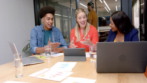 Happy-diverse-colleagues-with-laptops-and-tablet-in-discussion-at-casual-office-meeting,-slow-motion