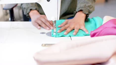 Biracial-female-fashion-designer-sewing-fabric-with-sewing-machine-in-studio,-slow-motion