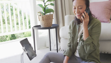 Mujer-Asiática-Feliz-Usando-Smartphone-Y-Tableta-En-El-Dormitorio,-En-Cámara-Lenta