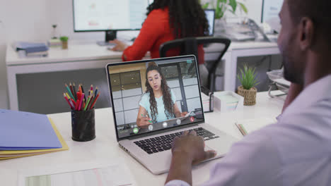 Video-De-Un-Hombre-Afroamericano-Teniendo-Una-Videollamada-En-Una-Computadora-Portátil-Con-Una-Compañera-De-Trabajo-Caucásica