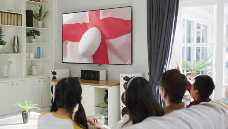 Familia-Asiática-Viendo-Televisión-Con-Una-Pelota-De-Rugby-En-La-Bandera-De-Inglaterra-En-La-Pantalla