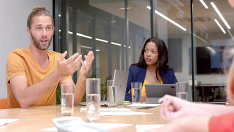 Caucasian-casual-businessman-talking-to-diverse-colleagues-at-office-meeting