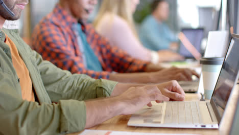 Mittelteil-Verschiedener-Geschäftskollegen,-Die-Im-Büro-Telefon-Headsets-Und-Laptops-Verwenden,-Zeitlupe