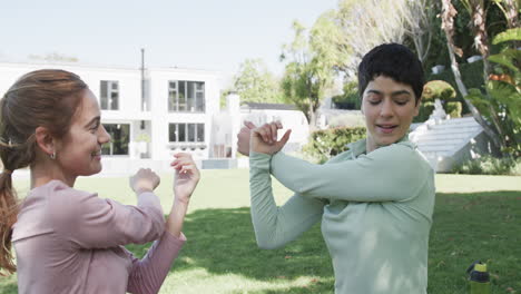 Happy-caucasian-lesbian-couple-stretching-in-sunny-garden,-slow-motion