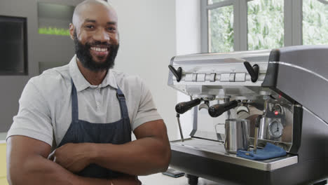 Porträt-Eines-Glücklichen-Afroamerikanischen-Barista-Mit-Verschränkten-Armen,-Der-In-Zeitlupe-Im-Café-Lächelt