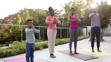 Happy-african-american-parents,-son-and-daughter-practicing-yoga-in-sunny-garden,-in-slow-motion