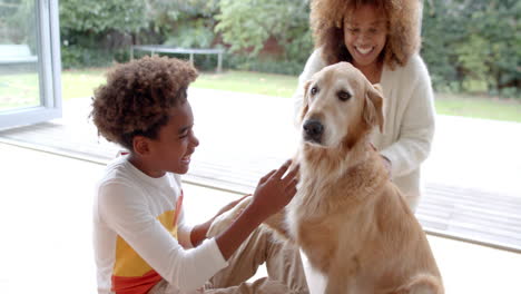 Glückliche-Afroamerikanische-Mutter-Und-Sohn-Sitzen-Auf-Dem-Boden,-Streicheln-Hund,-Zeitlupe