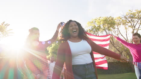 Happy-diverse-male-and-female-friends-dancing-with-flags-in-sunny-garden