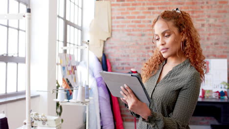 Nachdenkliche-Biracial-Modedesignerin-Mit-Tablet-Im-Studio,-Zeitlupe