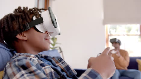 African-american-father-and-son-playing-video-game-using-vr-headsets-at-home,-slow-motion