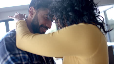 Happy-biracial-couple-embracing-and-smiling-at-home,-in-slow-motion