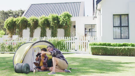 Caucasian-grandfather-and-grandson-by-tent,-looking-through-binoculars,-copy-space,-slow-motion