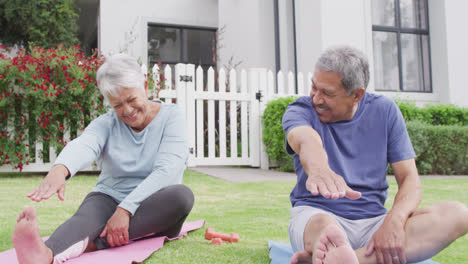 Happy-senior-diverse-couple-practicing-yoga-in-garden