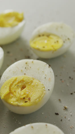 Video-of-close-up-of-peppered-halves-of-hard-boiled-eggs-on-grey-background