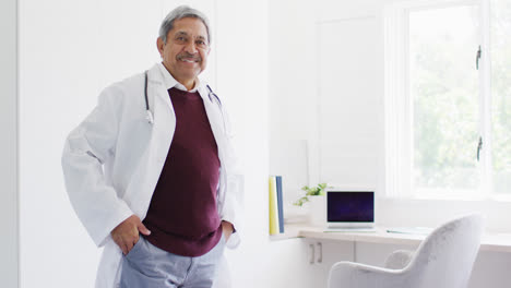 Retrato-En-Video-De-Un-Médico-Birracial-Parado-En-El-Consultorio-Con-Los-Brazos-Cruzados-Sonriendo-A-La-Cámara