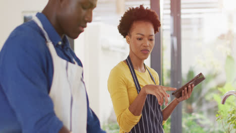 Video-of-happy-african-american-couple-cooking-together-with-tablet