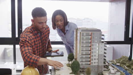 Diverse-male-and-female-architect-discussing-architectural-model-and-using-tablet,-slow-motion