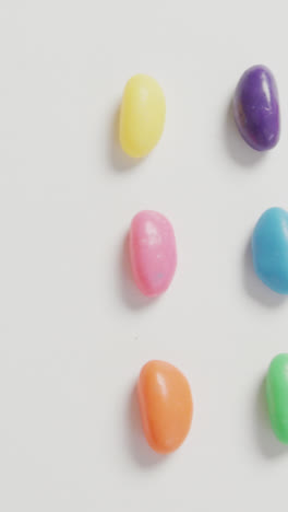 Video-of-overhead-view-of-rows-of-multi-coloured-sweets-with-copy-space-over-white-background