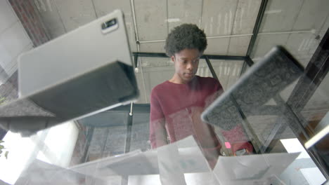 African-american-casual-businessman-with-documents-using-tablet-on-glass-table,-slow-motion