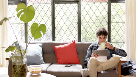 Biracial-man-working-from-home-using-tablet,-slow-motion,-copy-space