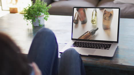 Knees-of-woman-at-table-using-laptop,-online-shopping-for-beauty-products,-slow-motion