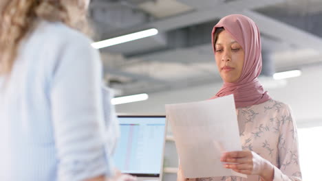 Diverse-creative-female-colleagues-in-discussion-using-documents-in-office,-slow-motion