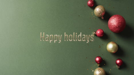 Frohe-Feiertage-Text-Mit-Glitzernden-Weihnachtskugeln-Auf-Grünem-Hintergrund
