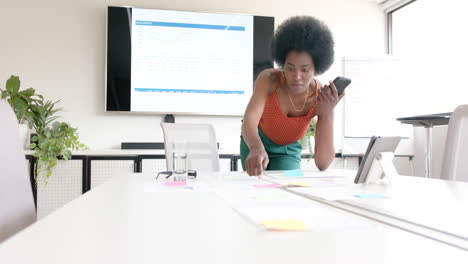 Mujer-De-Negocios-Informal-Afroamericana-Y-Hablando-Por-Teléfono-Inteligente-En-La-Sala-De-Juntas,-Cámara-Lenta