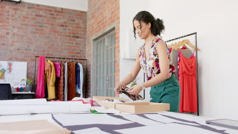 Biracial-Modedesignerin-Verpackt-Kleidungsbestellung-Im-Studio,-Kopierraum,-Zeitlupe