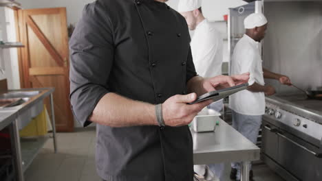 Caucasian-male-chef-using-tablet-in-kitchen,-slow-motion