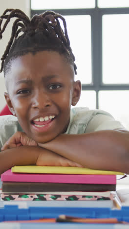 Video-of-happy-african-american-boy-sitting-at-school-desk