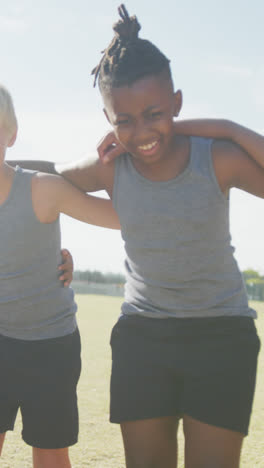 Video-of-happy-diverse-boys-walking-on-grass-and-holding-arms